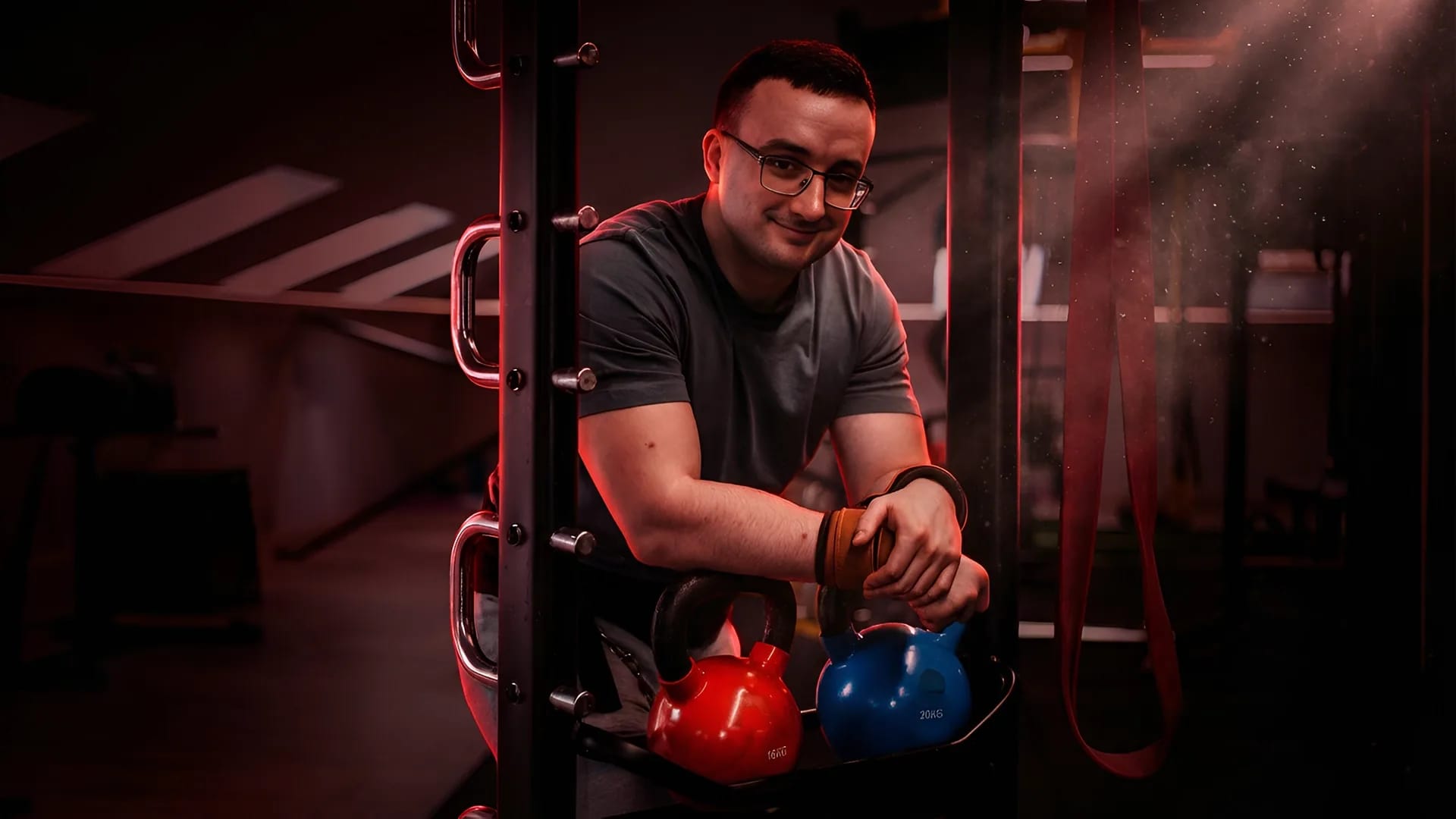 Trainer Milan Jovandić im Fitnessstudio, an ein Kettlebell-Regal gelehnt